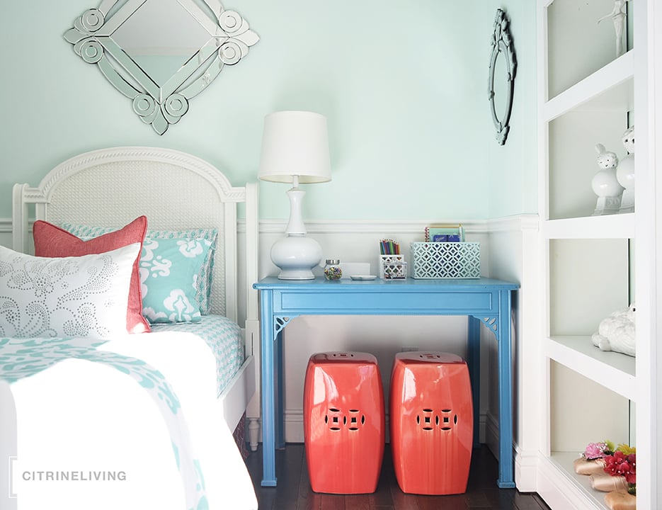 Girl's bedroom featuring turquoise desk as nigh table and coral garden stools.