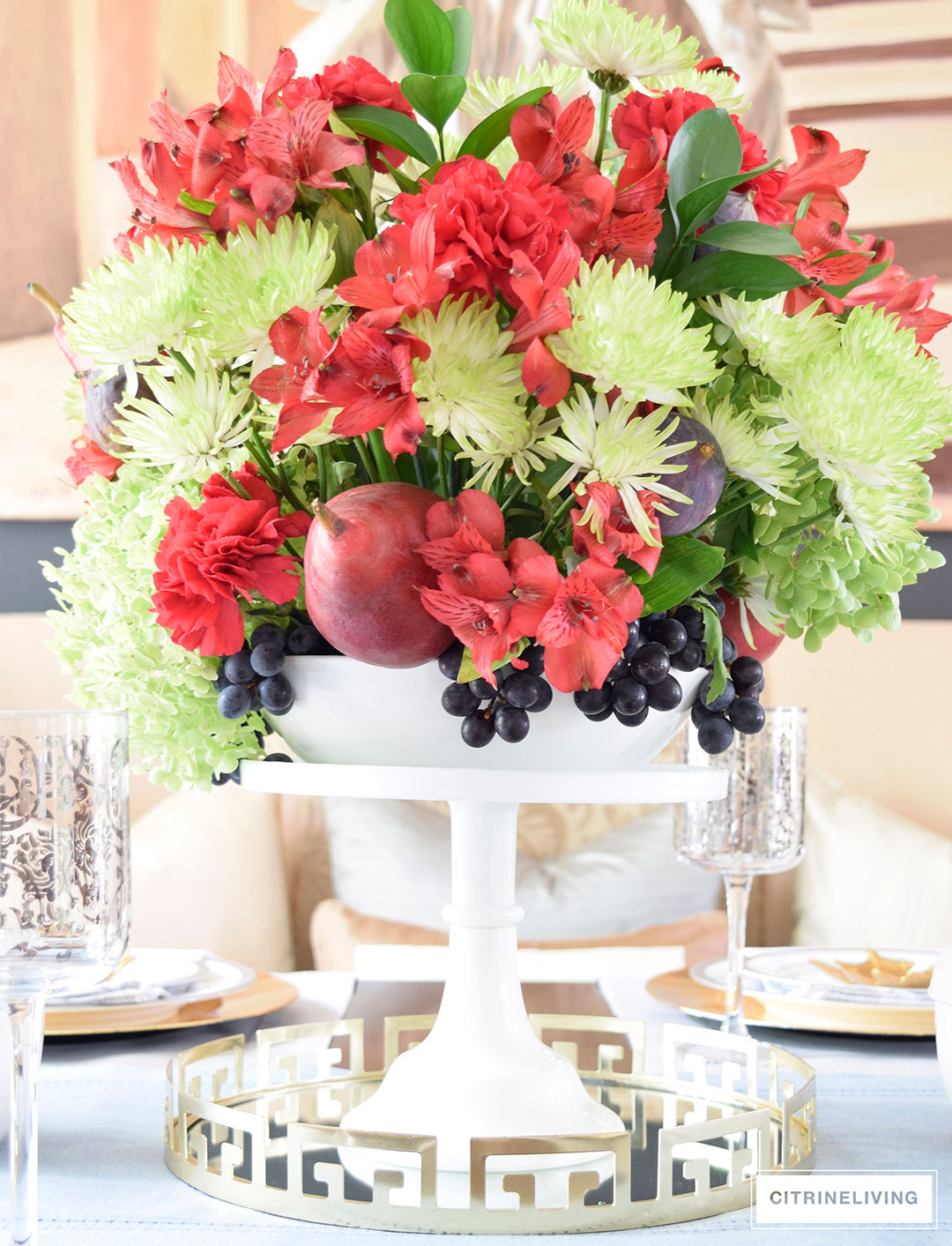Fall tablescape with metallic touches featuring vibrant red, deep plum and verdant green centrepiece