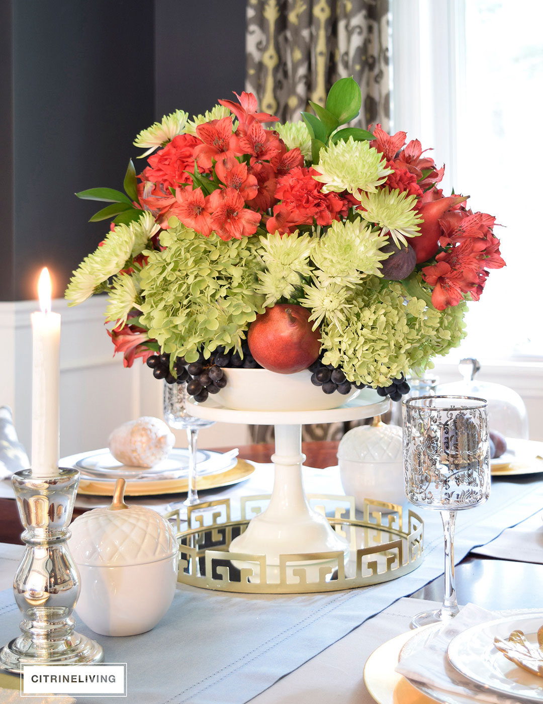 Fall tablescape with metallic touches featuring vibrant red, deep plum and verdant green centrepiece