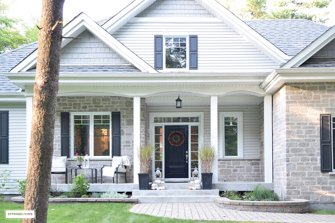Grey and white hime exterior with black details - Fall porch decor featuring mercury glass pumpkins and potted grass 