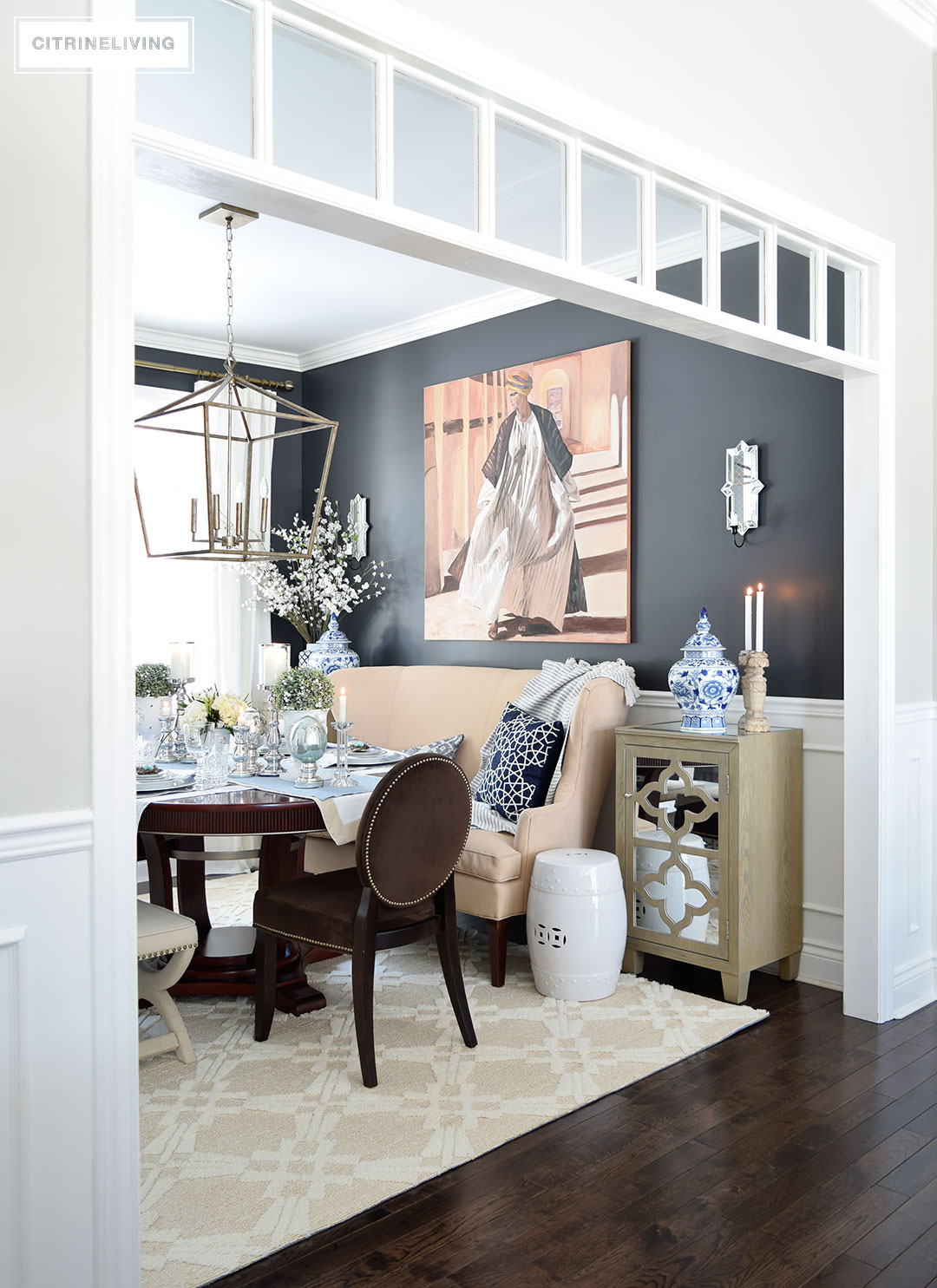 Elegant dining room with black walls and blue and white chinoiserie accents. White transoms add architectural interest. A simple Easter or Spring tablescape with metallic accents adds sophistication.