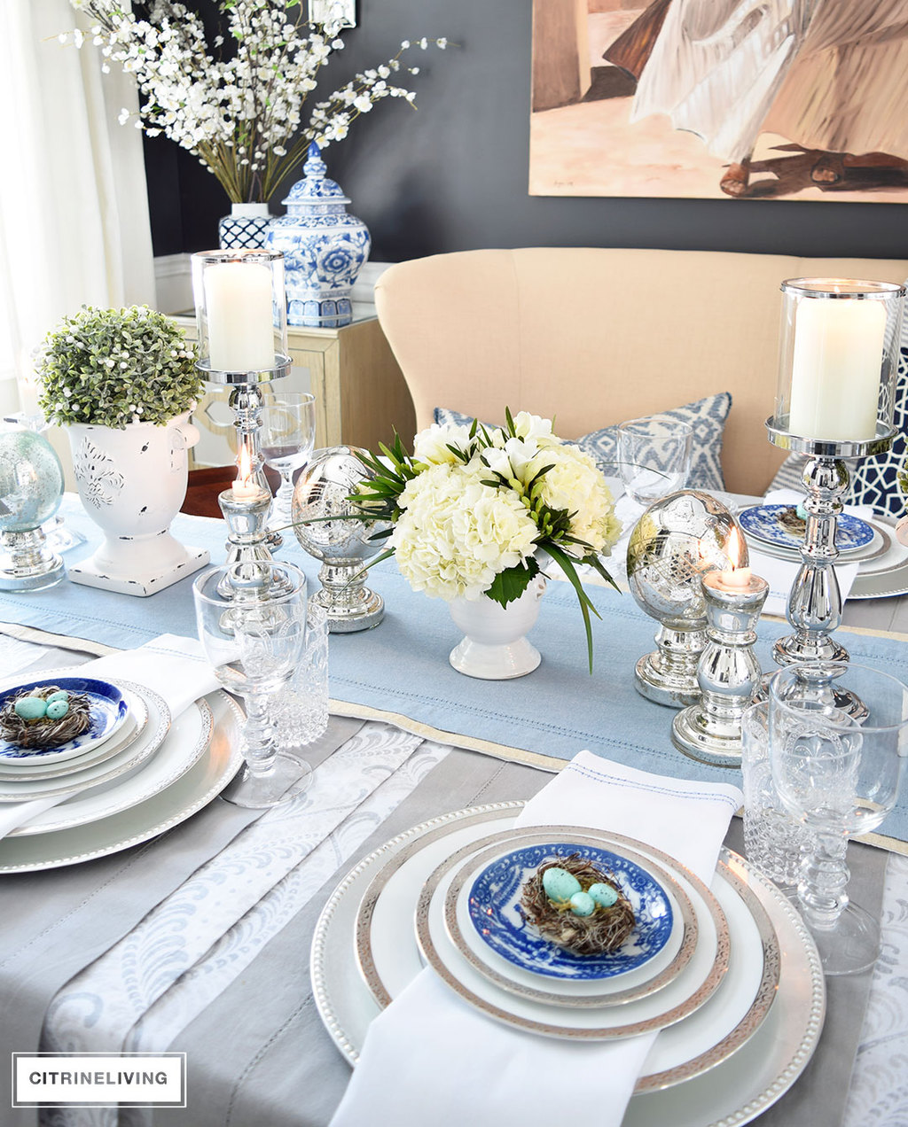 A gorgeous Easter tablescape with mercury glass accents and a mix of silver and white with blue and white china. Fresh and beautiful white hydrangeas are the perfect centerpiece.