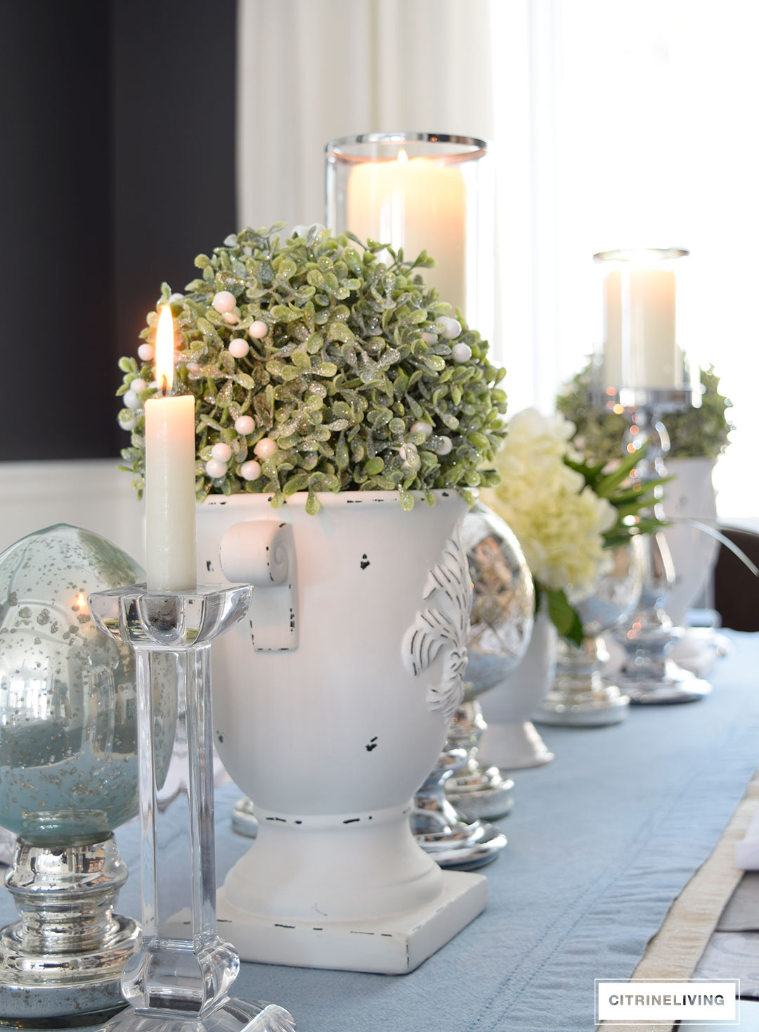 Easter or Spring tablescape with topiaries set in white urns, mixed with mercury glass and crystal accents.