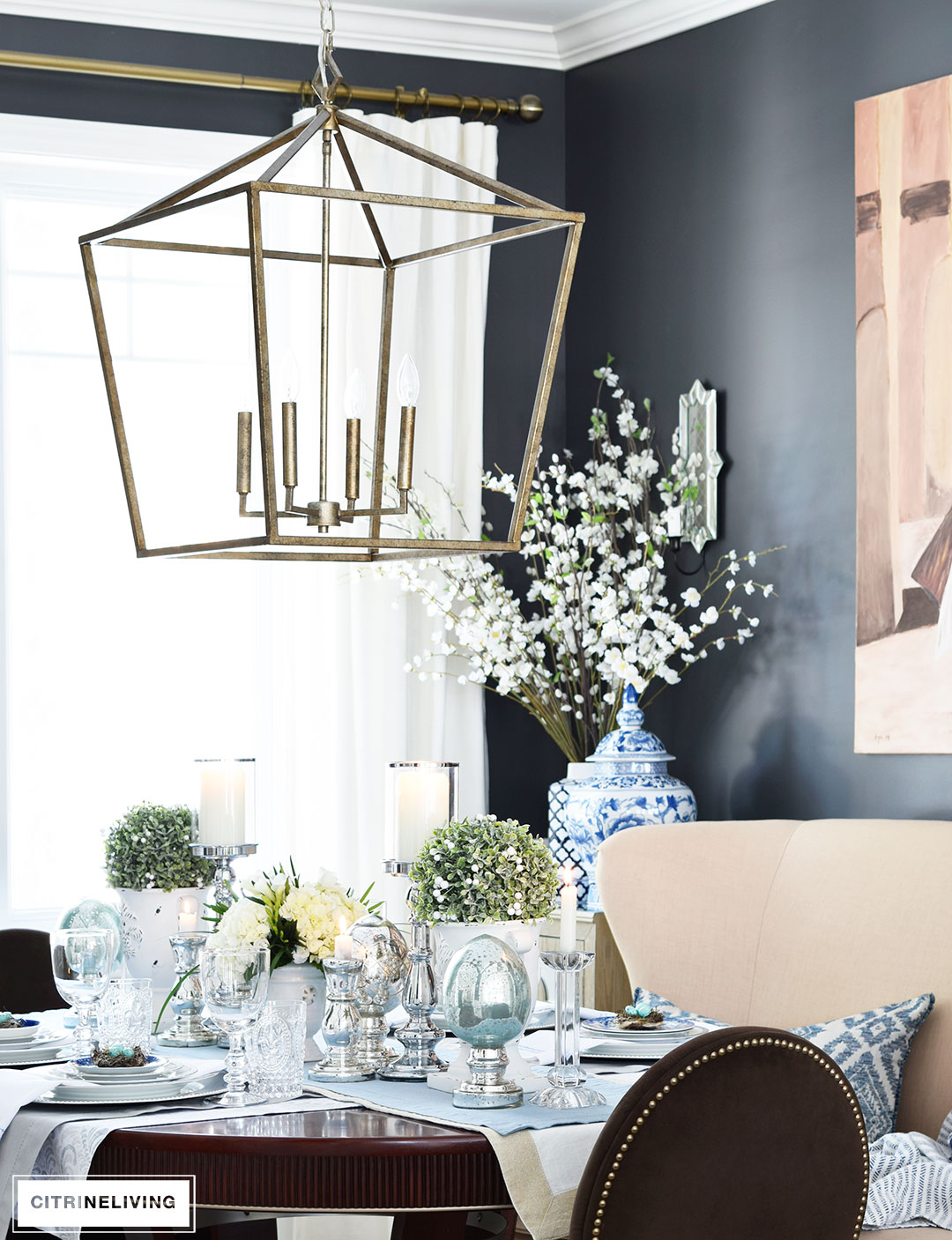 Modern, lantern style pendant chandelier hangs over an elegant Easter tablescape.