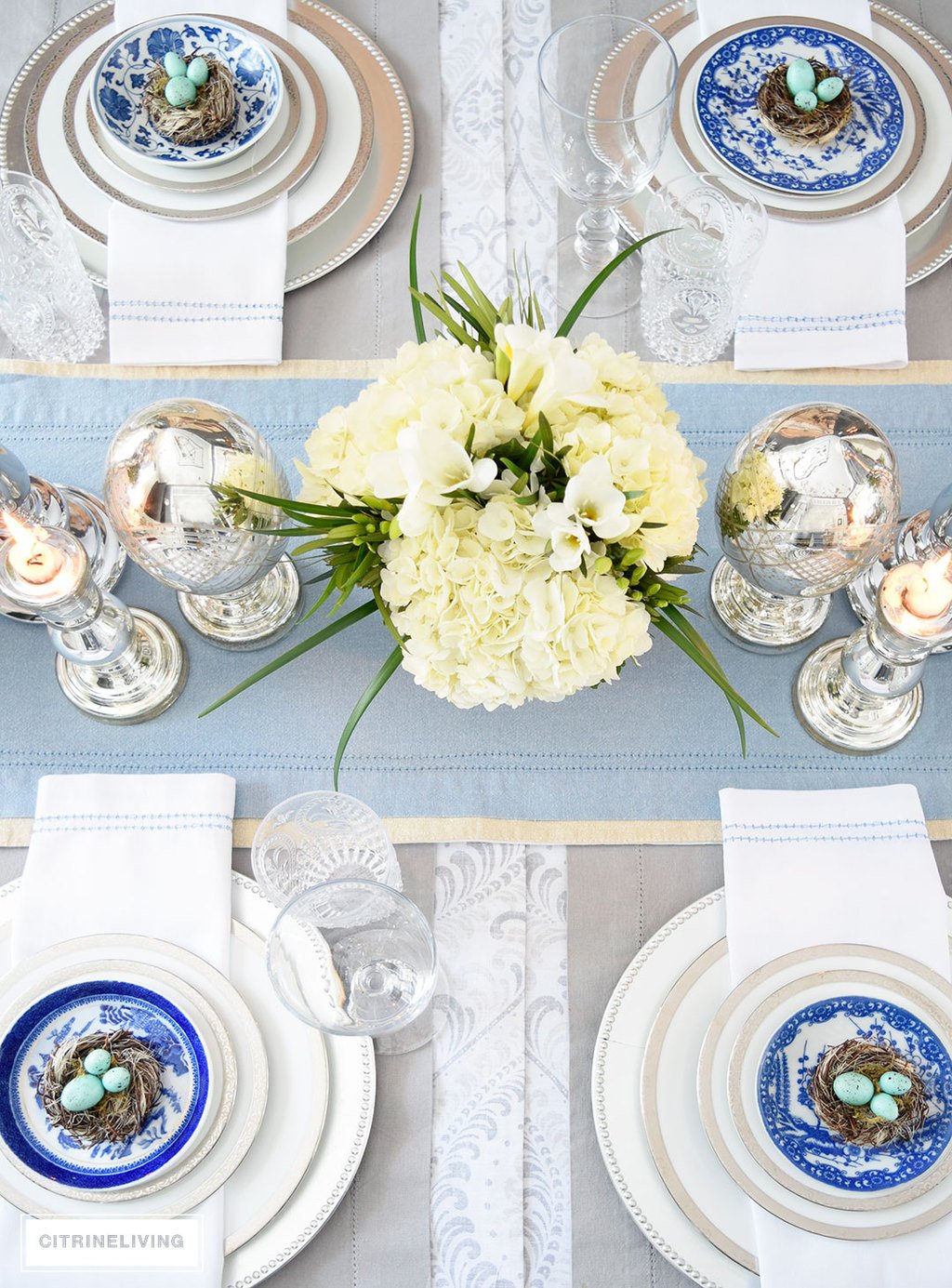 A gorgeous Easter tablescape with mercury glass accents and a mix of silver and white with blue and white china. Fresh and beautiful white hydrangeas are the perfect centerpiece.