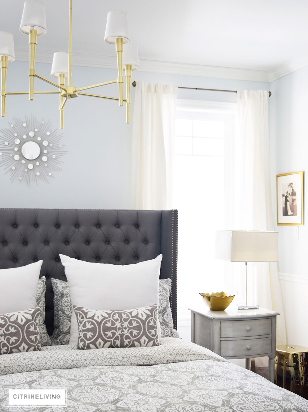 A brass chandelier and accents add modern sophistication to this elegant bedroom.