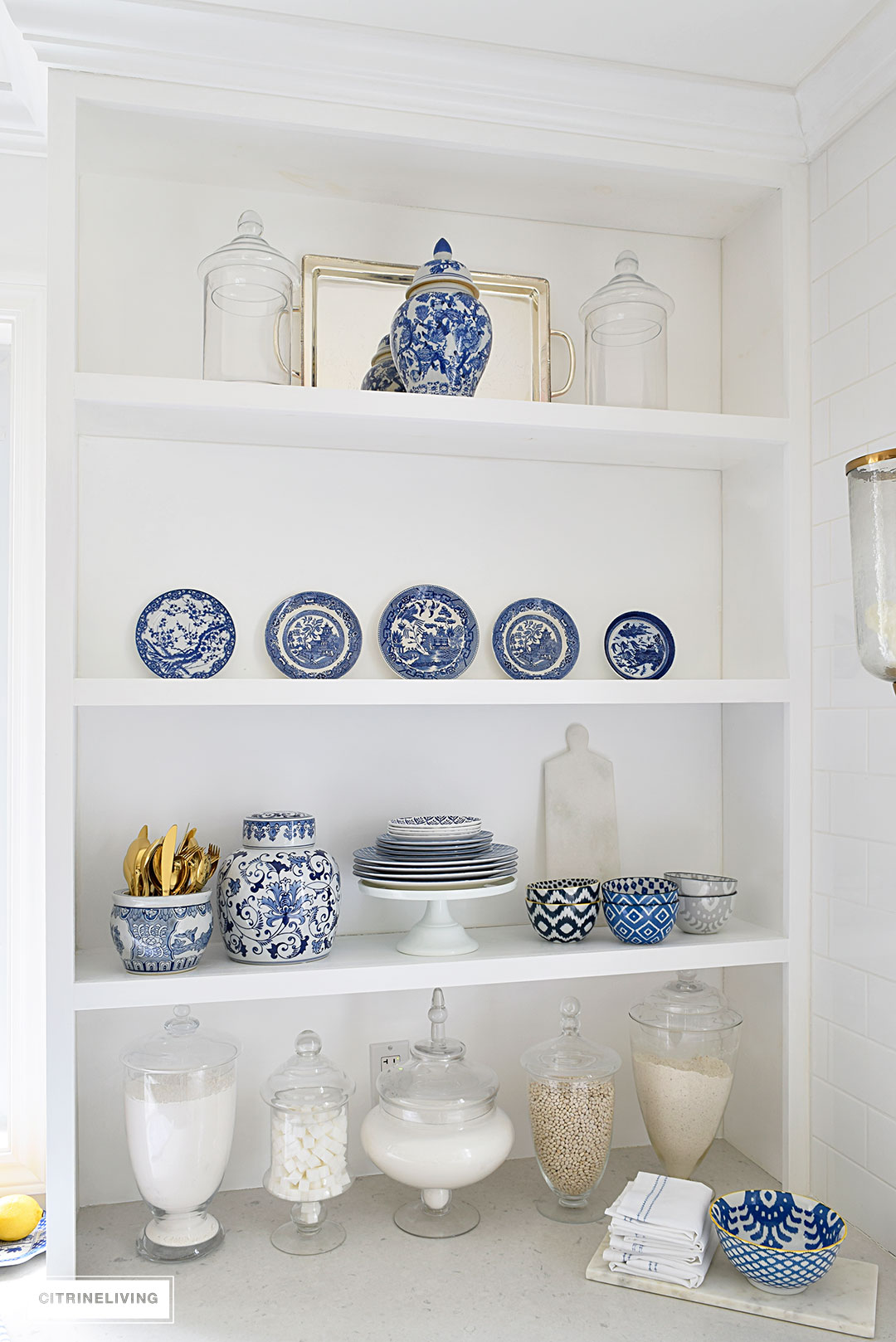 A gorgeous display of blue and white accessories and dishware on open shelving is sophisticated and elegant. 