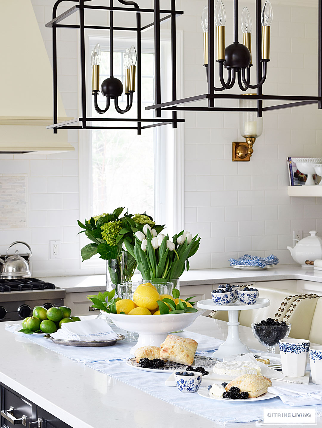 A white kitchen with a welcoming tablescape of blue and white accented with fresh flowers, lemons and limes.