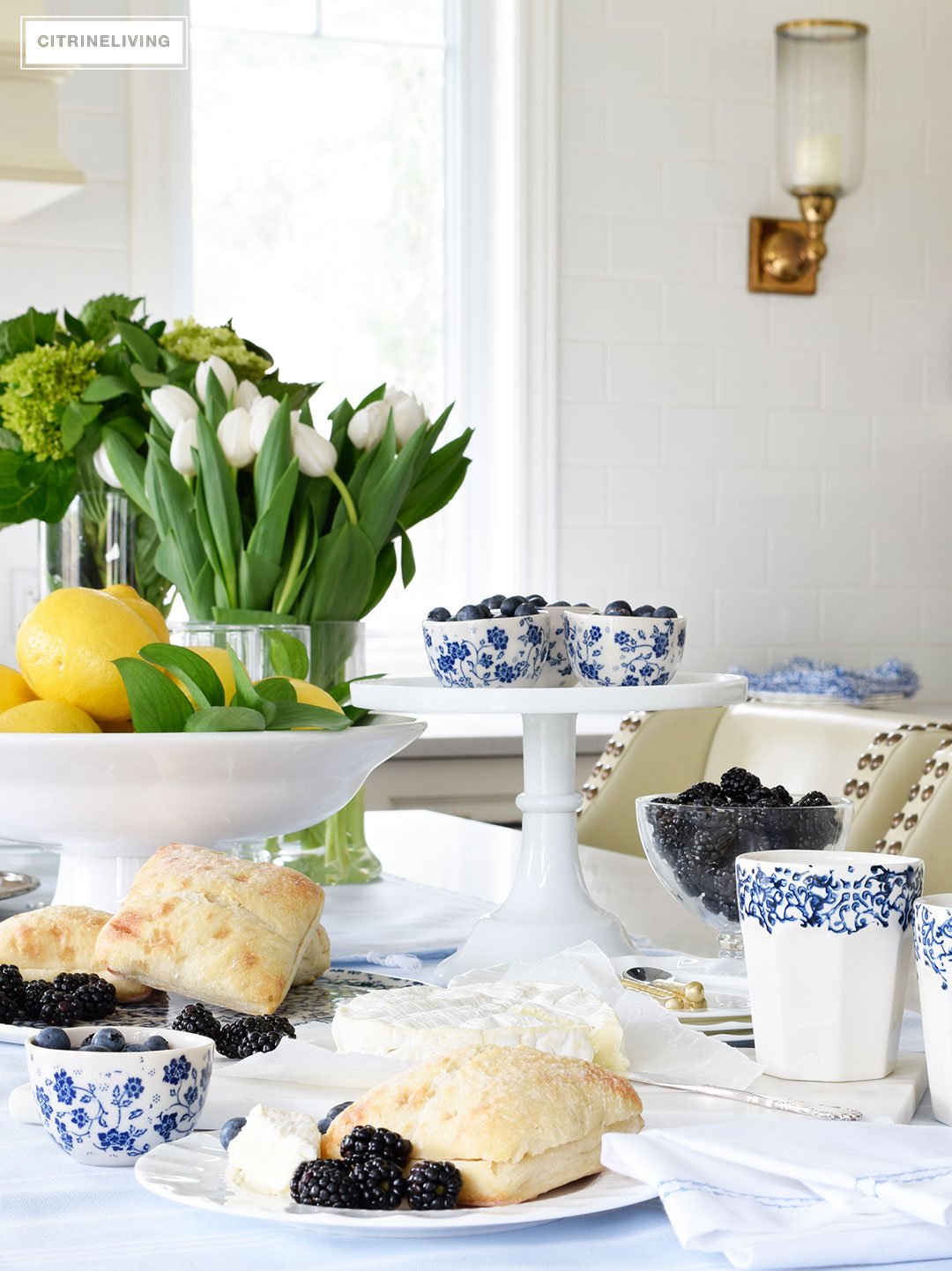 Create a welcoming tablescape of blue and white accented with fresh flowers, lemons and limes.