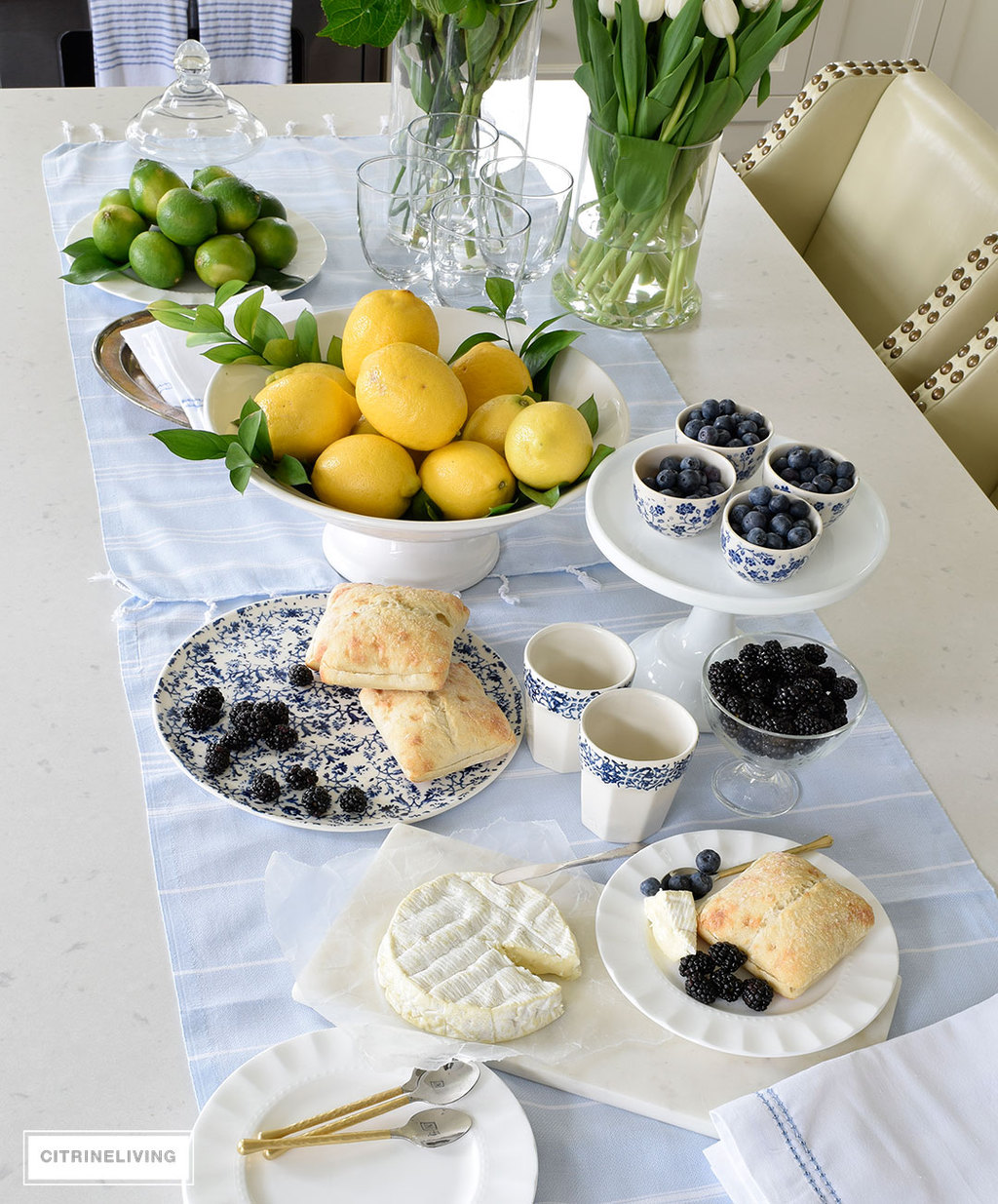 Create a welcoming tablescape of blue and white accented with fresh flowers, lemons and limes.