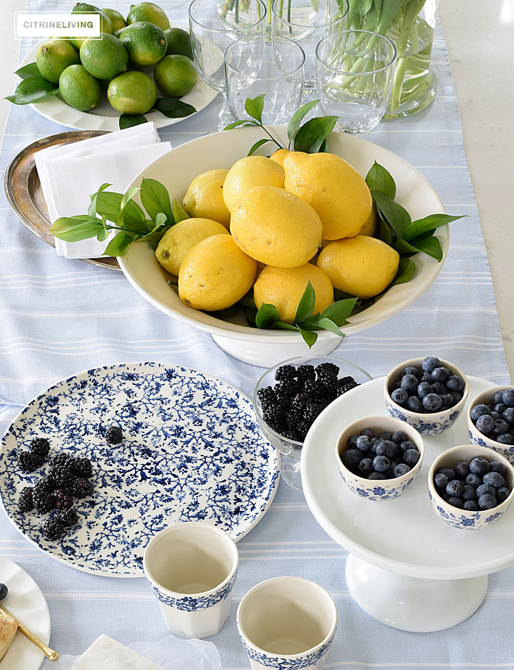 Create a welcoming tablescape of blue and white accented with fresh flowers, lemons and limes.