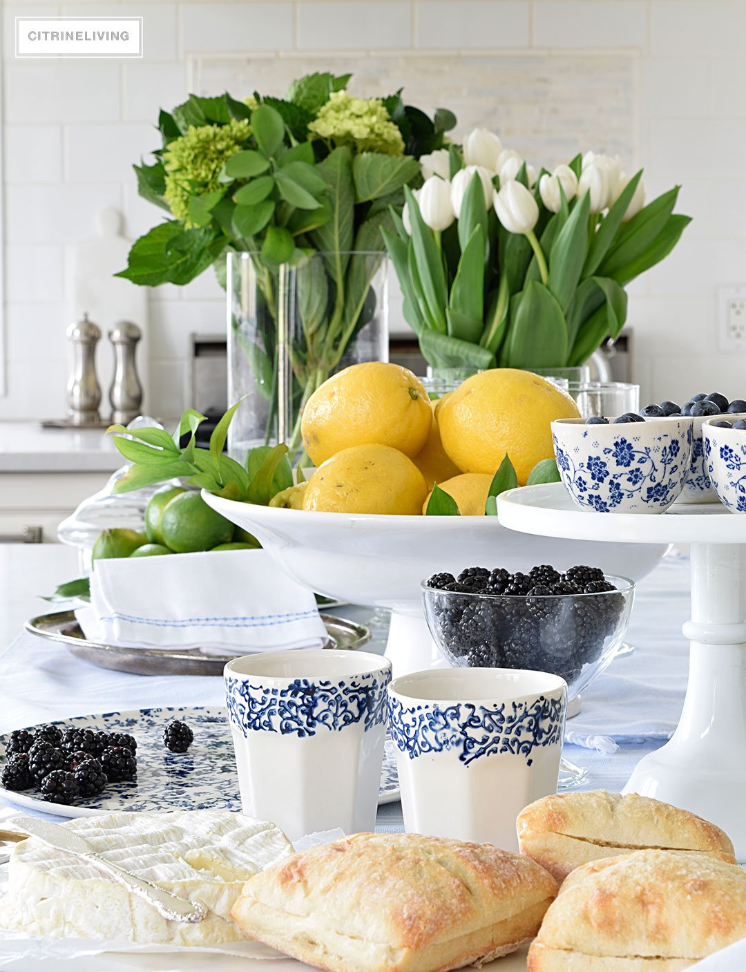 Create a welcoming tablescape of blue and white accented with fresh flowers, lemons and limes.