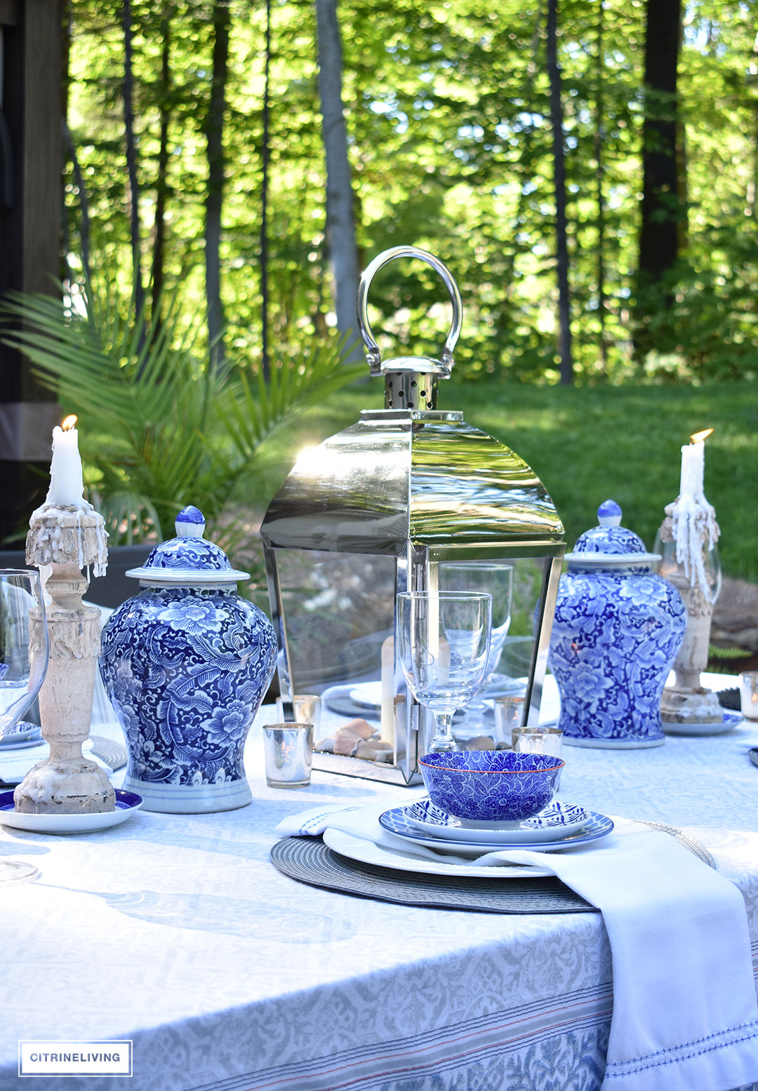 Beautiful outdoor tablescape with a silver lantern flanked by blue and white ginger jars