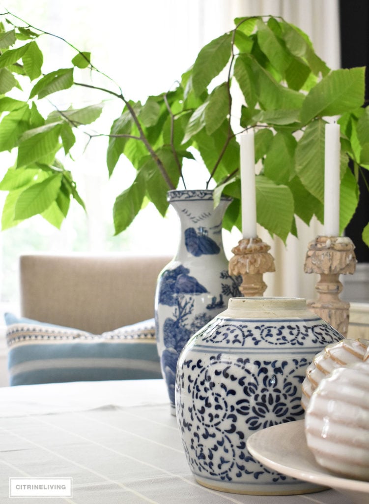 Blue and white vases and ginger layered with textured neutrals create a soothing and classic look, Fresh cut greenery is a simple and elegant touch of Summer decor.