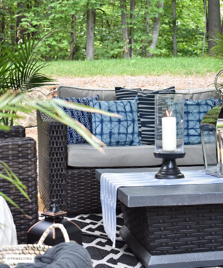 Create the perfect lounging area in your backyard with a beautiful covered gazebo, with added height for an airy, open feel. A gorgeous fire table, solar chandelier, resin wicker furniture, and layered accessories create an elegant and sophisticated look.