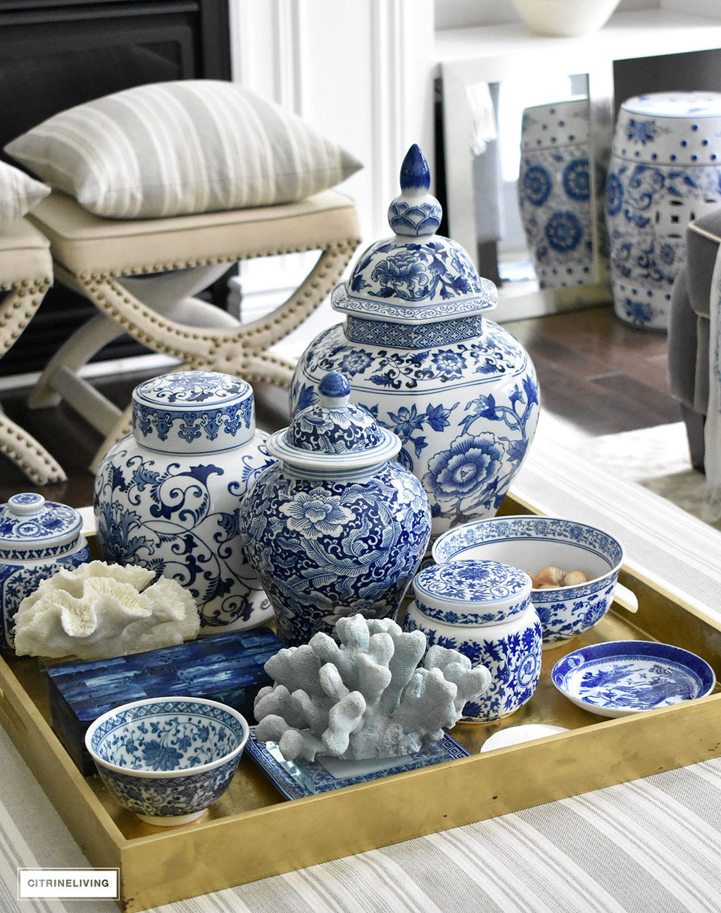 Living room ottoman arranged with blue and white ginger jars, vases and bowls on a gold tray