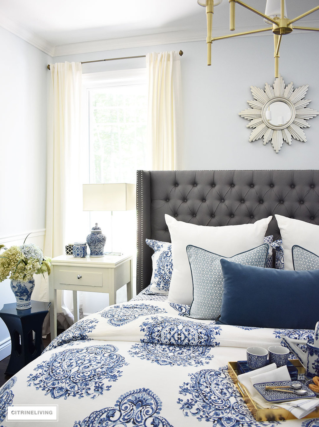 A sunburst mirror is a chic and classic addition to any space! This beautiful blue and white bedroom accented with a mix of cool and warm metals is elegant, warm and inviting. A metallic sunburst mirror as the perfect finishing touch.
