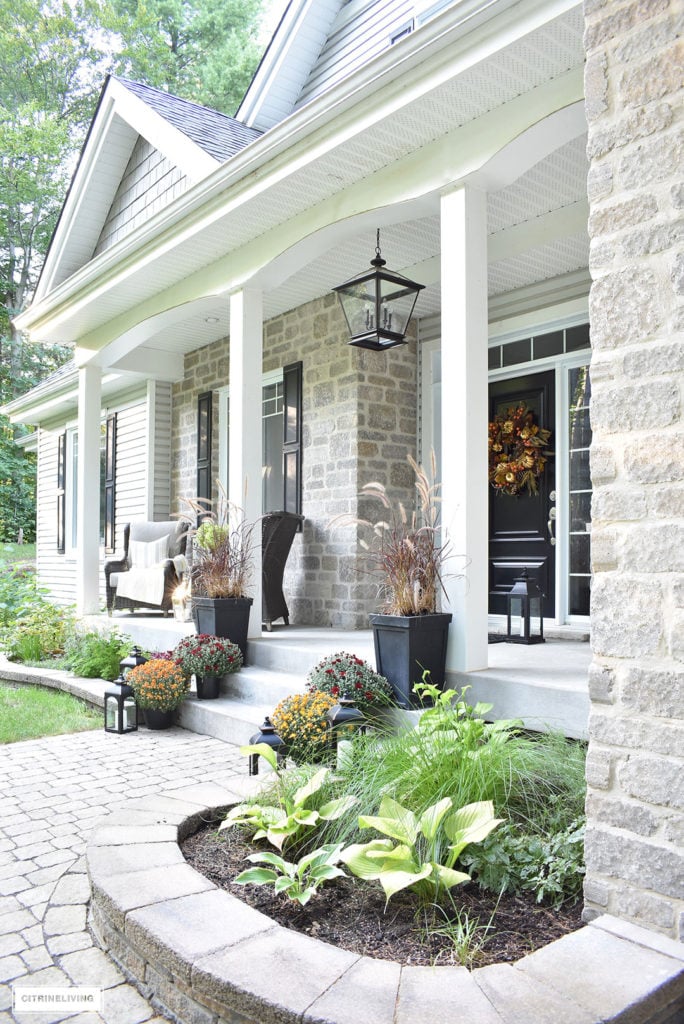 Front porch decorated for Fall using mums, fall plants and a rich sophisticated wreath