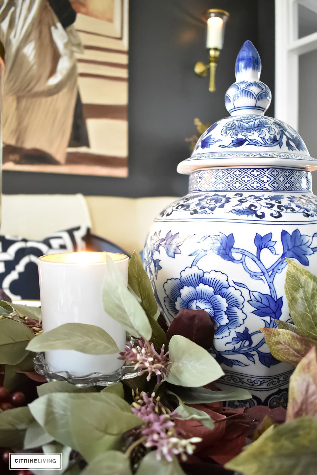 Create an elegant Fall tablescape using faux foliage in rich, autumnal hues, paired with gold, black and white tableware, and blue and white chinoiserie.