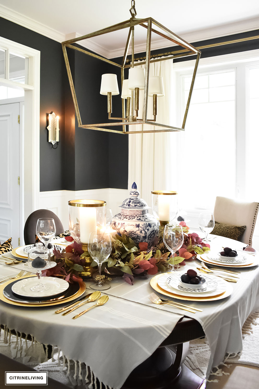 Create an elegant Fall tablescape using faux foliage in rich, autumnal hues, paired with gold, black and white tableware, and blue and white chinoiserie.
