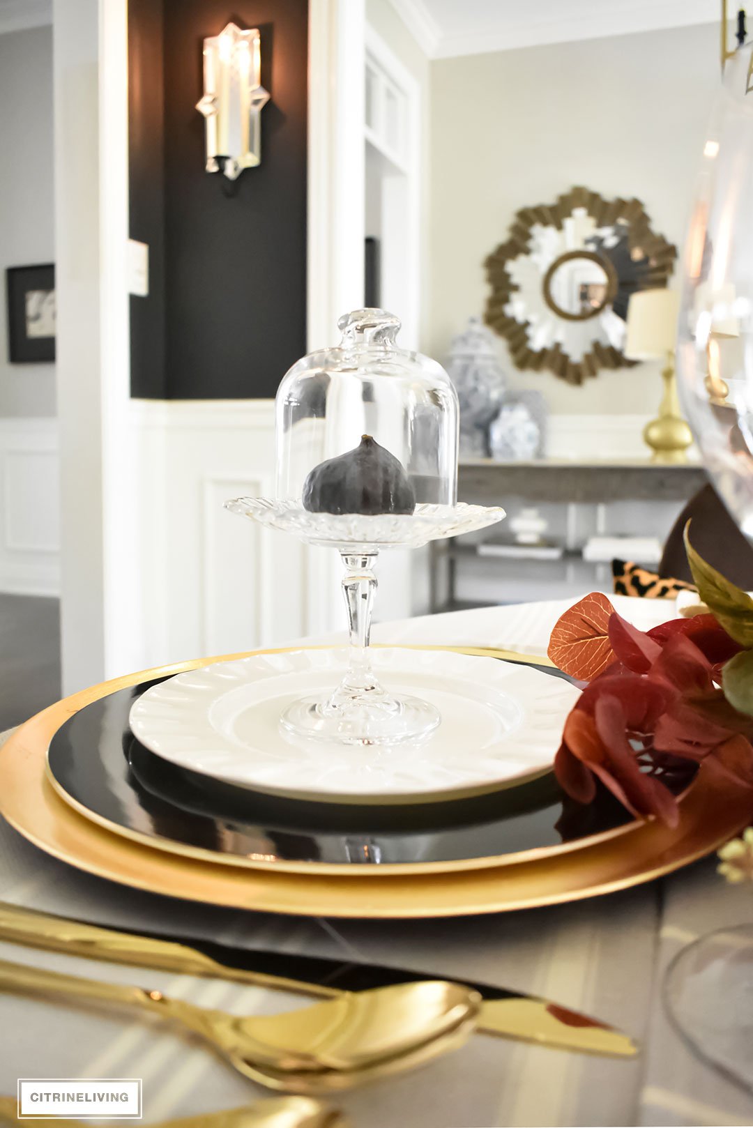 Create an elegant Fall tablescape using faux foliage in rich, autumnal hues, paired with gold, black and white tableware, and blue and white chinoiserie.