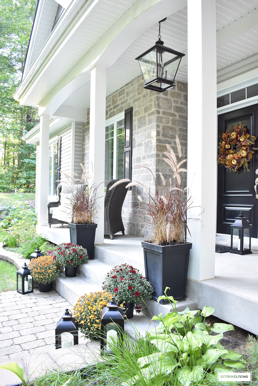 A simple and elegant front porch decorated for Fall with seasonal flowers in autumnal colors, and a sophisticated overscale wreath for the front door.