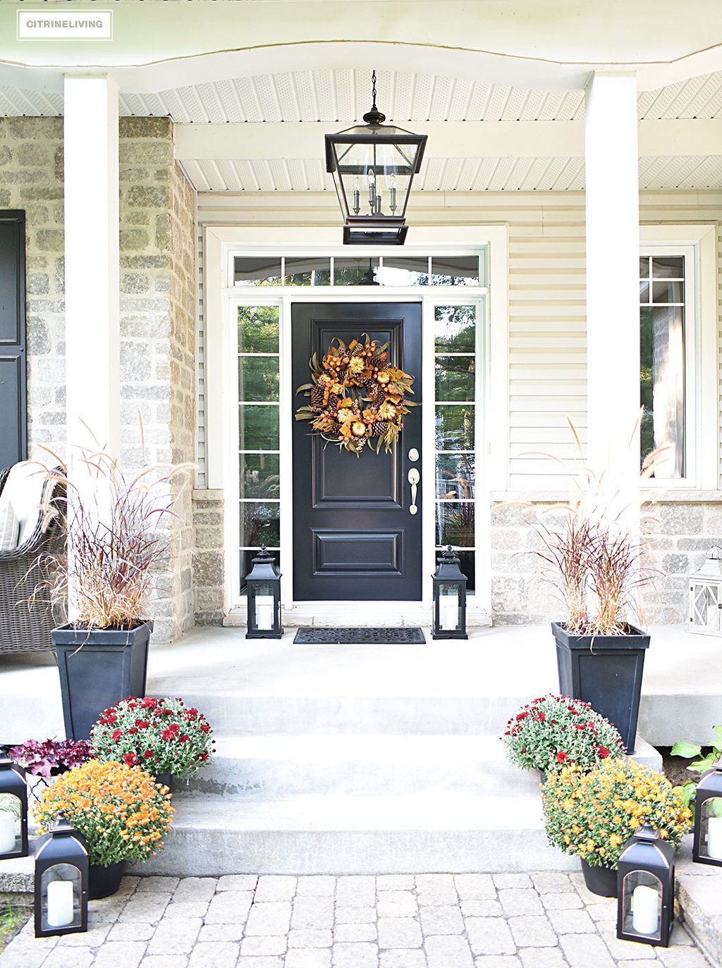 A simple and elegant front porch decorated for Fall with seasonal flowers in autumnal colors, and a sophisticated overscale wreath for the front door.