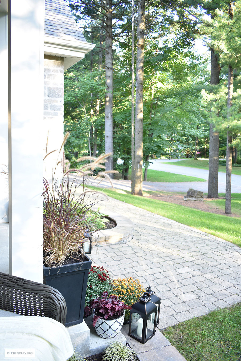 A simple and elegant front porch decorated for Fall with seasonal flowers in autumnal colors, and a sophisticated overscale wreath for the front door.