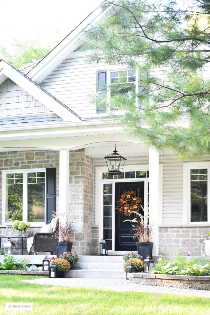 Front porch decorated for Fall using mums, fall plants and a rich sophisticated wreath