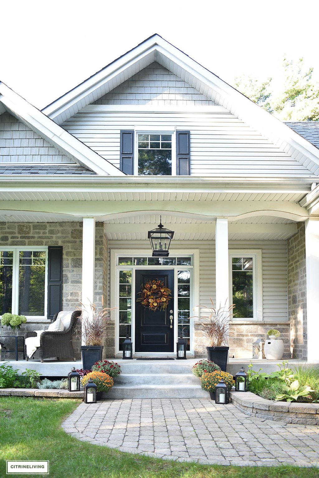 A simple and elegant front porch decorated for Fall with seasonal flowers in autumnal colors, and a sophisticated overscale wreath for the front door.