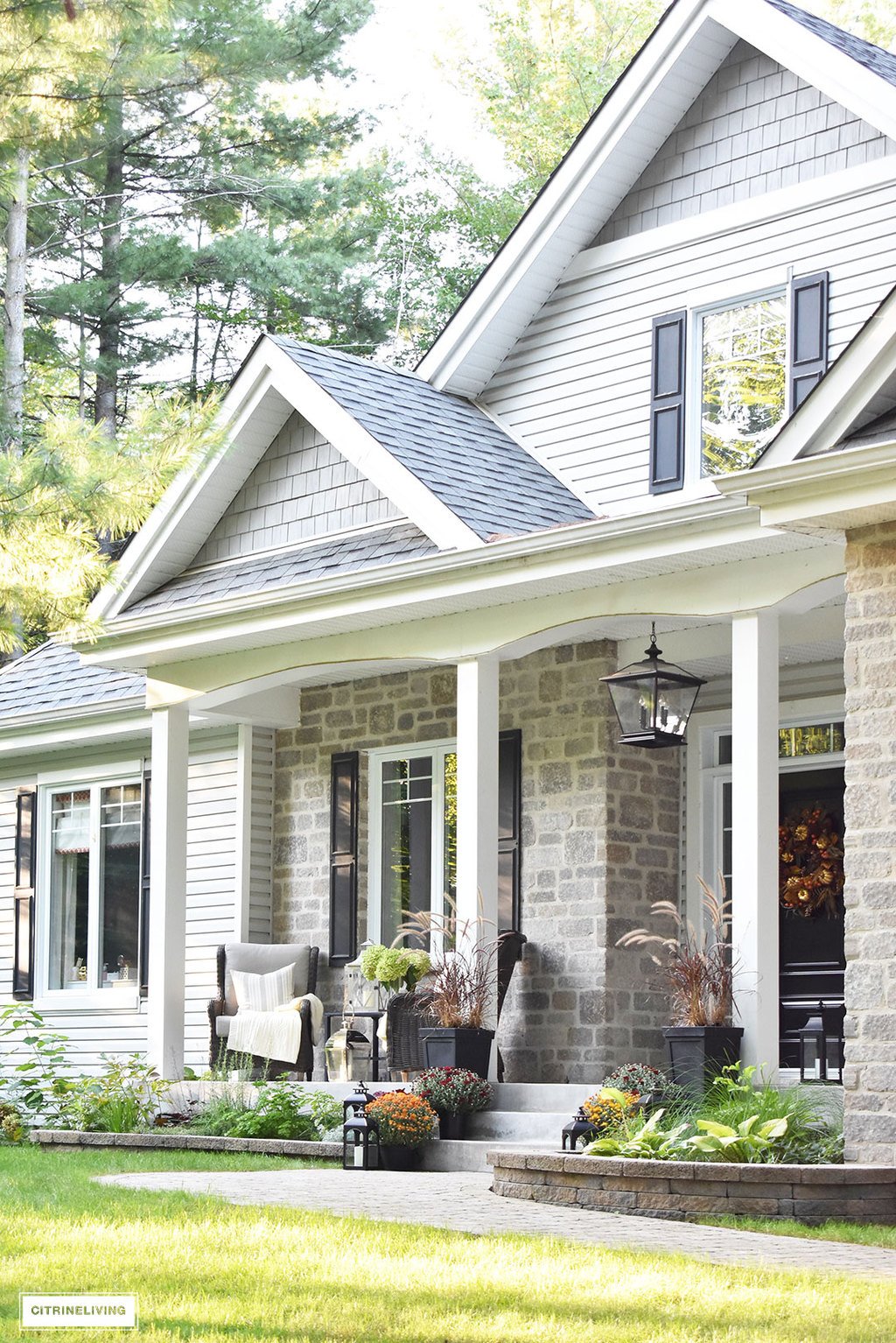 A simple and elegant front porch decorated for Fall with seasonal flowers in autumnal colors, and a sophisticated overscale wreath for the front door.