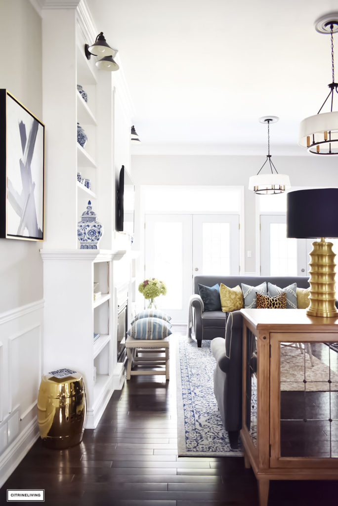 Fall Home Tour featuring this elegant living room with sophisticated navy and gold accents, drum shade chandeliers, gray sofas and blue and white accessories. Blue vintage style rug.