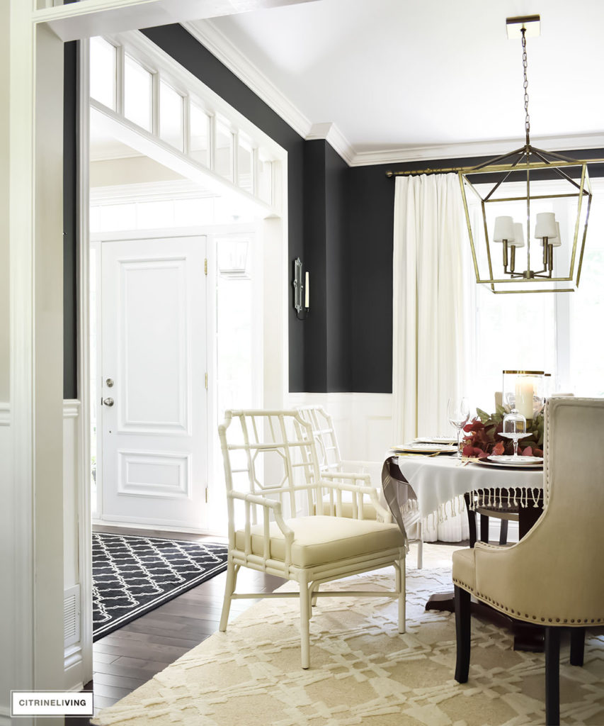 Fall Home Tour. Black dining room with elegant furniture. Leopard pillows. Brass overscale lantern style chandelier. Blue and white accents. Upscale lattice-back white chairs from Selemat.