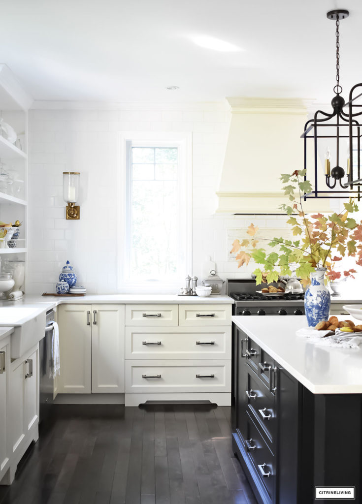 Fall Home Tour - casual elegant black and white kitchen with large black island and lantern style pendant lighting. Blue and white vases and Fall foliage.