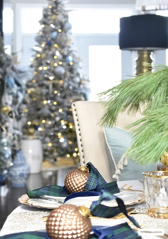 Gorgeous Christmas tablescape with classic navy and green tartan, accented with gold ornaments, chargers, flatware and glassware.