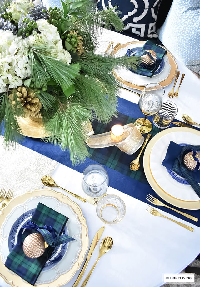 Gorgeous Christmas tablescape with classic navy and green tartan, accented with gold ornaments, chargers, flatware and glassware.