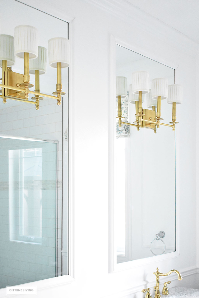 Gorgeous master bathroom makeover with custom mirrors, brass wall sconces and fixtures, + elegant white panelling!