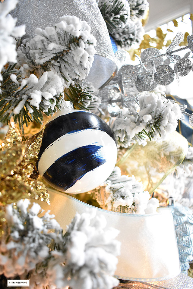Beautiful, flocked Christmas tree adorned with navy, light blue and elegant metallics, is sophisticated and refreshing for your holiday decor.
