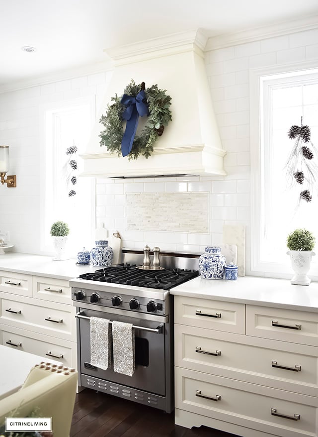 A beautiful Christmas kitchen with blue and white chinoiserie, paired with holiday greenery for a sophisticated, festive and elegant look.