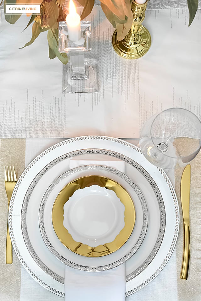 A gorgeous neutral Valentine's table with tones of white layered with metallic accents and a beautiful white rose centrepiece.