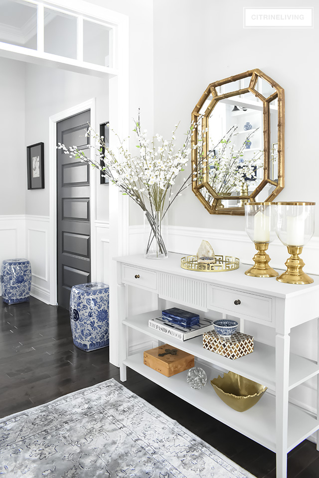 Entryway with a light grey console table, gold, glass and blue accessories are classic and elegant.