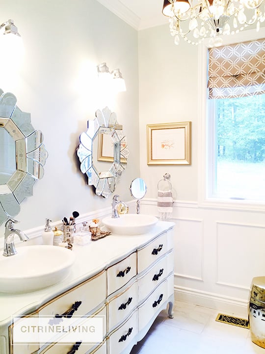 Bathroom with vintage dresser as vanity and venetian mirrors.