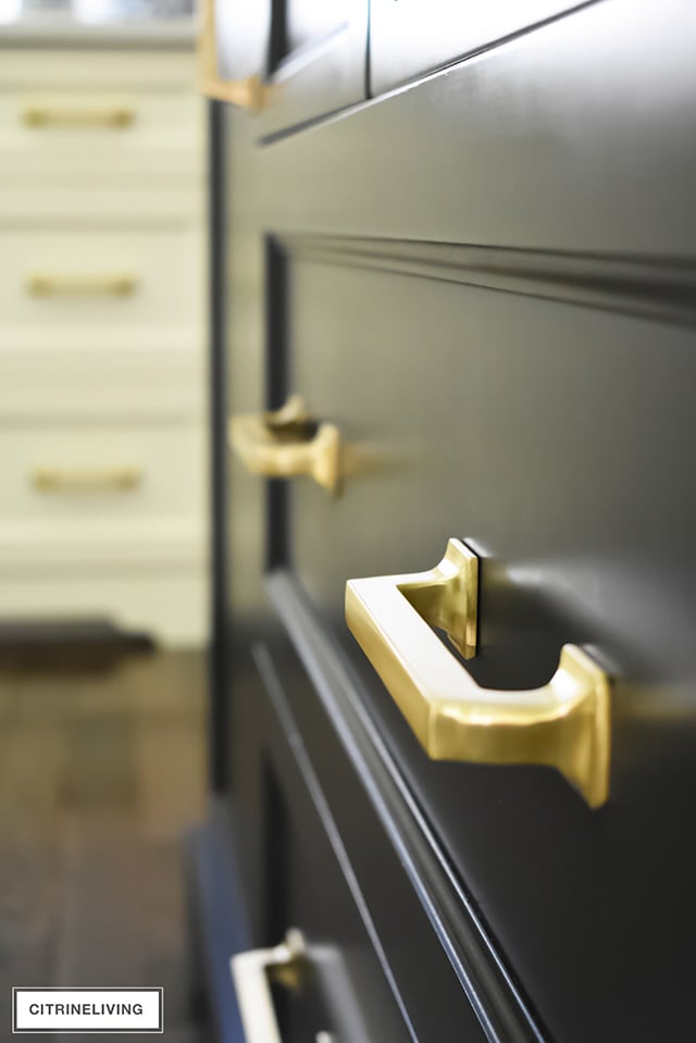 Brass hardware pulls on black kitchen island drawers.