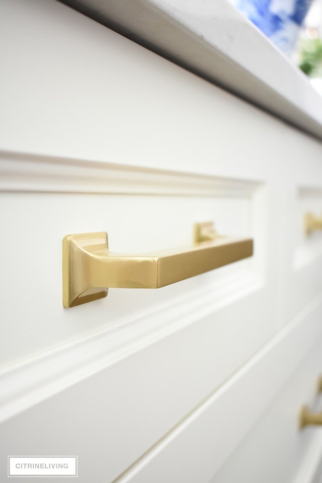 Brass hardware pulls on ivory kitchen drawers.