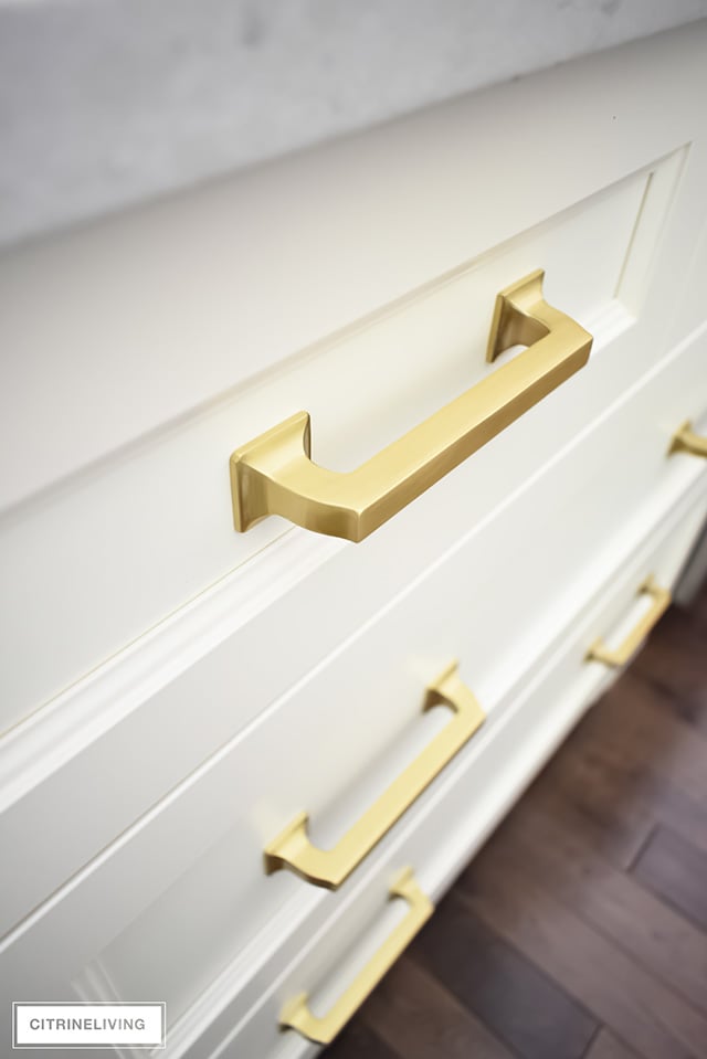 Ivory cabinets with brass hardware pulls.