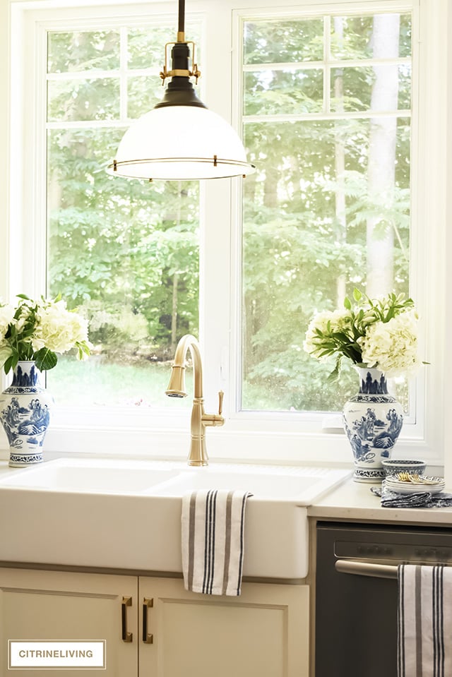 White kitchen with farm sink, industrial pendant light and brass faucet.