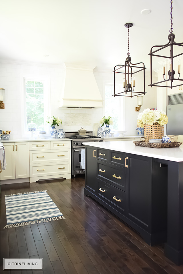 White kitchen with black island, pendant lighting over island, oak hardwood floors.