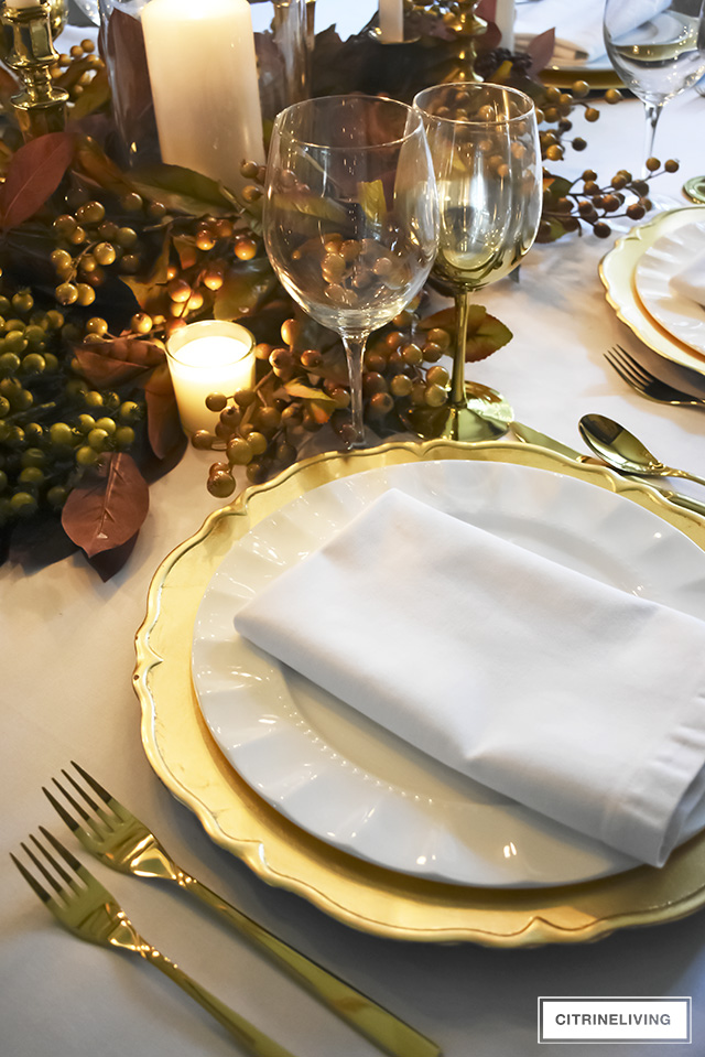 A white and gold Thanksgiving tablescape, with beautiful fall foliage in warm, earthy tones is a simple and elegant way to entertain for the holidays!