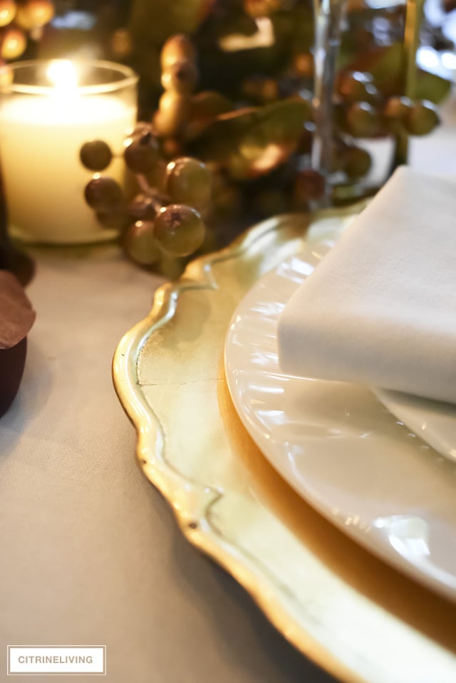 A white and gold Thanksgiving tablescape, with beautiful fall foliage in warm, earthy tones is a simple and elegant way to entertain for the holidays!