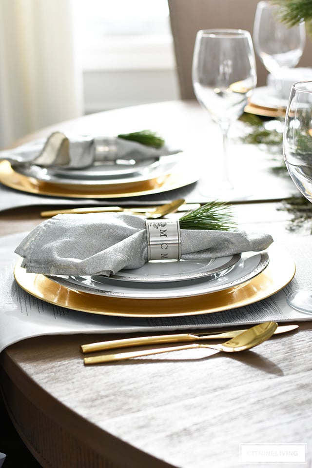 Beautiful Christmas tablescape with fresh greenery, silver and gold china and antique silver napkin rings.